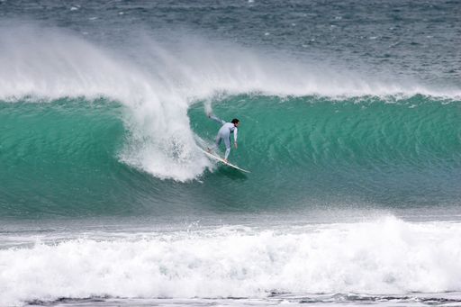 A young male surfer riding the big waves on a sunny day