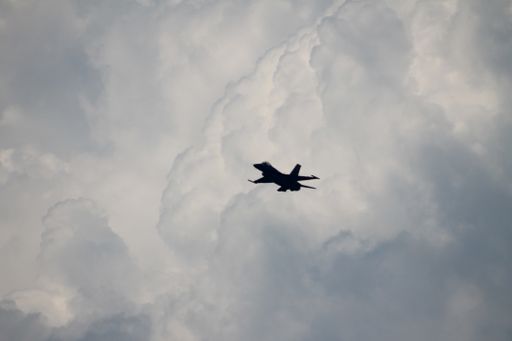 A low angle shot of an airplane flying in the air under the beautiful fluffy clouds
