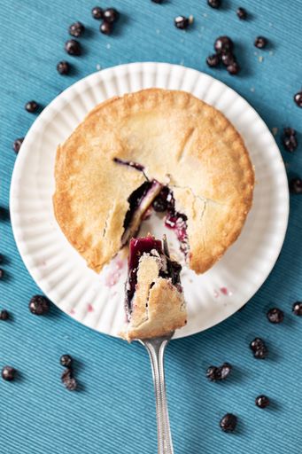 A vertical top view of a blueberry pie with a fork taking a slice out