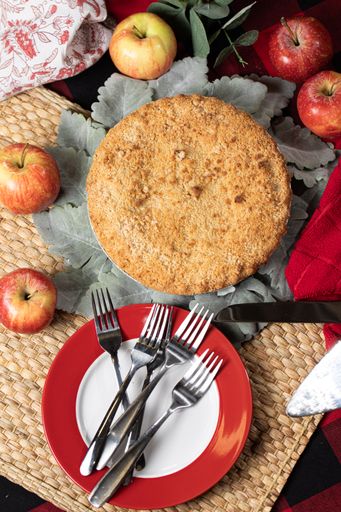 A vertical shot of a fresh apple pie and apples on a dinner table