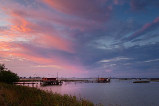 A beautiful shot of a lagoon at Comacchio Valleys under a pink cloudy sky during the sunset