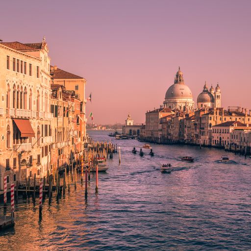 A beautiful shot of boats in the canal with the famous Basilica of Saint Mary of Health in the background at a sunset