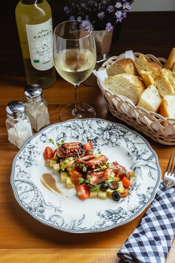 Italian food setup with grilled octopus, vegetables, and white wine, Canggu, Bali
