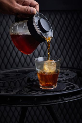 A vertical shot of a person pouring coffee into a glass in a restaurant in Bali