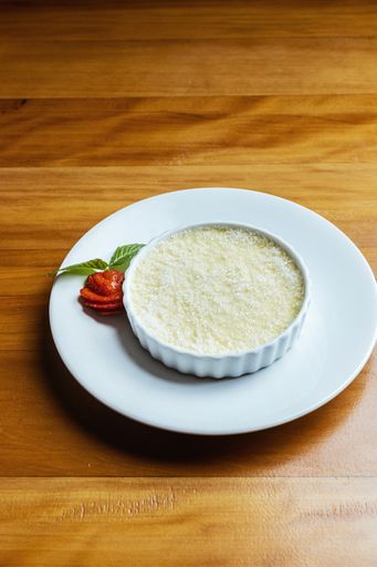 A vertical shot of a white dessert on a plate on a wooden surface
