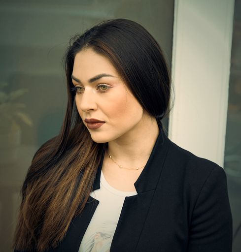 A portrait of a beautiful, long haired Hispanic business woman in an office