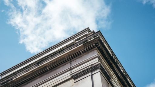 A low angle shot of an architectural building under a clear blue sky with white clouds