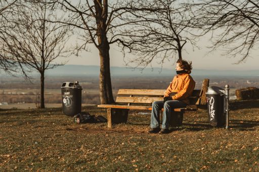 A person in an orange jacket sits on a park bench overlooking scenic Lahr, Germany