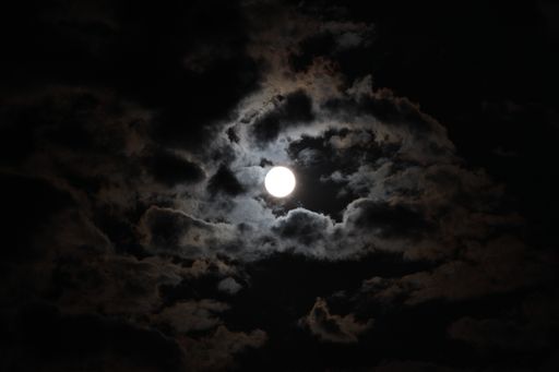 A beautiful view of the full moon and clouds in the dark night sky
