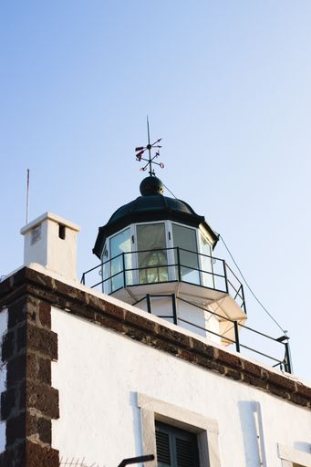 A low angle shot of a white lighthouse in Santorini
