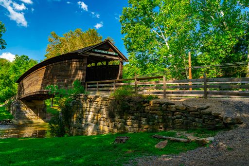 Historic Humpback Bridge in Virginia surrounded by vibrant green trees and a clear blue sky.