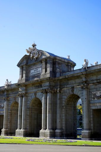 A side beautiful view of the old gate of Puerta de Alcala in Madrid, Spain against a blue sunny sky