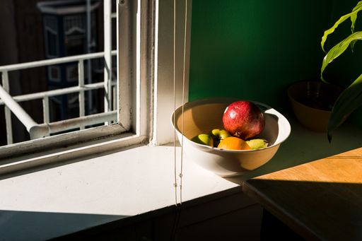 A high angle shot of fruits in a bowl near the window
