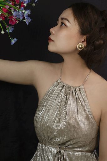 A vertical shot of a beautiful Asian girl with flowers on a black background