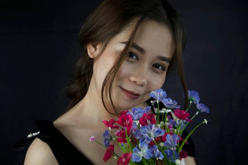 A closeup shot of a beautiful Asian girl with flowers on a black background