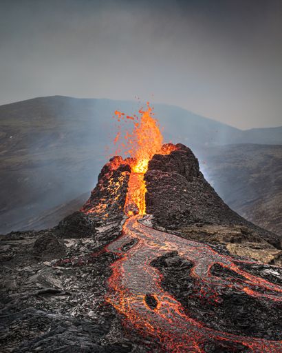 A beautiful shot of an active volcano with flowing lava and smoke under a clear sky
