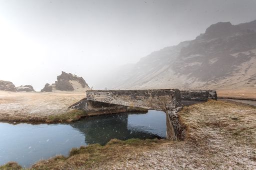 A beautfiul view of a stone bridge over the river under the blue sky