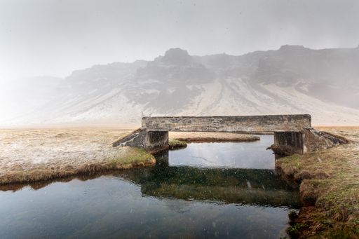 A beautfiul view of a stone bridge over the river under the blue sky