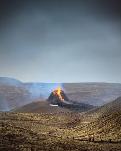 A beautiful shot of an active volcano with flowing lava and smoke under a clear sky