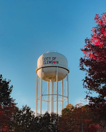 A vertical of a water tower with the writing "City of Clemson" among autumn trees in the USA