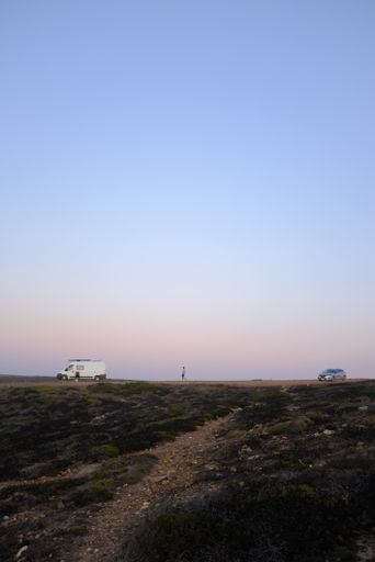 A vertical shot of cars on a desert with a clear blue sky in the background