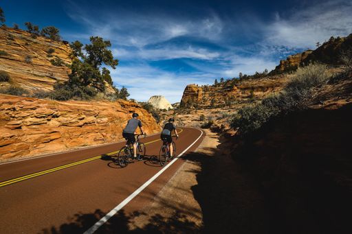 A view of an asphalt road between canyon rocky cliffs against a cloudy sky in Arizona, USA