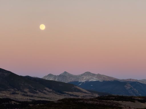 Moon rising over mountain peaks with soft sunset colors in sky off of Interstate 70 near Dillon