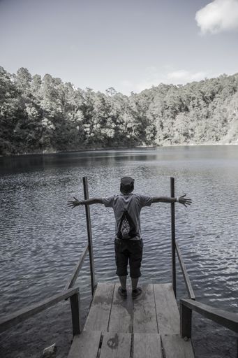 A beautiful vertical grayscale shot of a happy male near the Montebello lake in Chiapas, Mexico