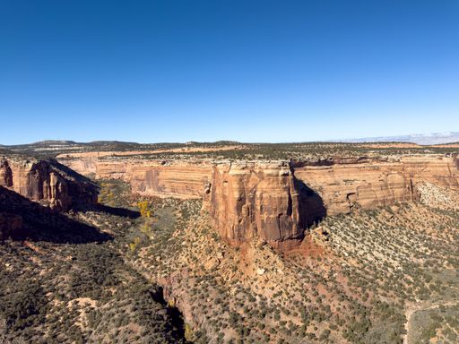 Ute canyon in colorado national monument with red cliffs rugged terrain and blue sky in a wide scenic view