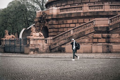 A solo traveler walks by Mannheim's Wasserturm and sphinx statues, blending history with modern urban life.