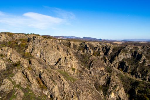Scenic view of rocky mountains under a clear blue sky, showcasing rugged terrain and natural beauty.