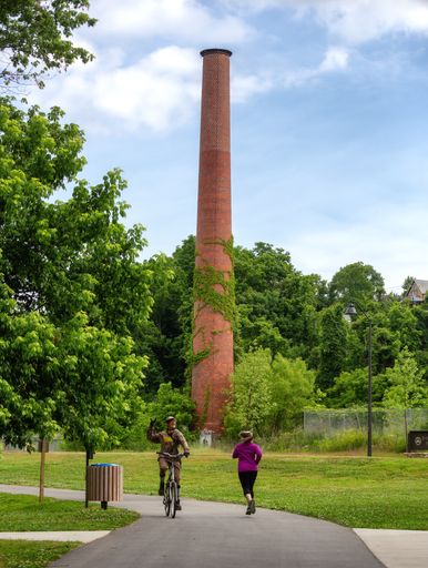 A vertical shot of some people walking in a park under the cloudy skies
