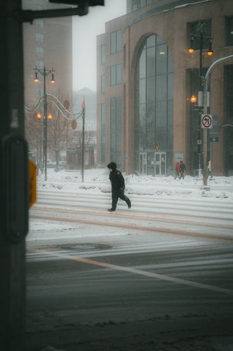 A vertical shot of some people walking at a street on a foggy cold day in winter