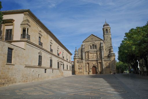 Historic urban square with a sandstone building featuring flags and balconies
