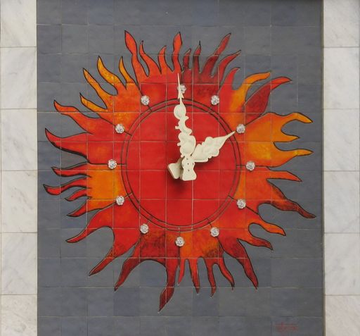 A big clock like a sun on a tiled wall