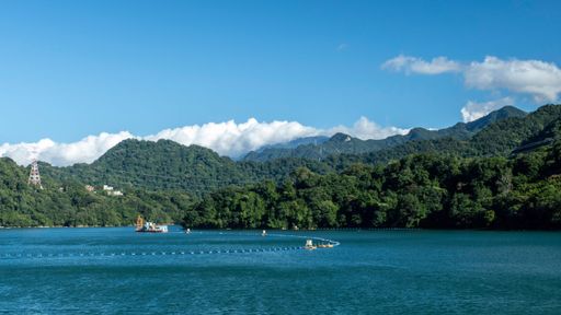 Scenic view of lush green mountains and a serene lake under a bright blue sky in Taiwan.