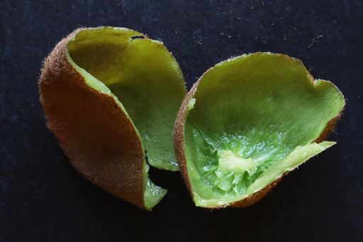 A top view of kiwi peels on a slate d background