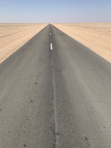 A vertical shot of an empty highway in a desert