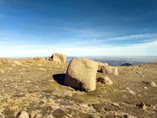 Large granite boulders rest on the alpine tundra near the summit of Pikes Peak with plains visible in the distance