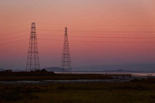 Two high voltage pylons against a blue and pink ombre sky