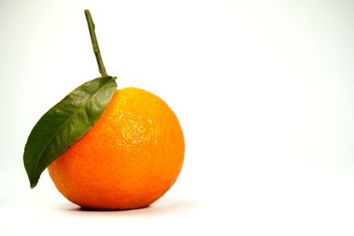 Whole orange fruit with a vibrant green leaf and stem, sitting on a white background, promoting healthy eating
