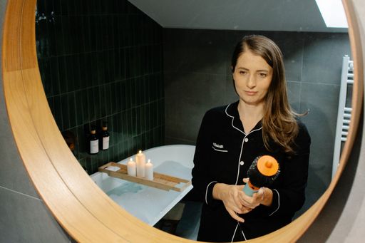Woman standing in bathroom mirror holding a hairbrush, creating a serene wellness moment