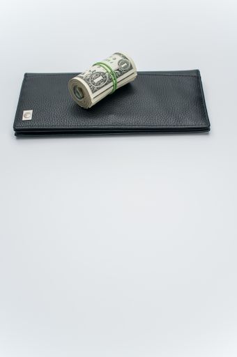 US dollars wad with luxury black leather wallet on a white background with copy space