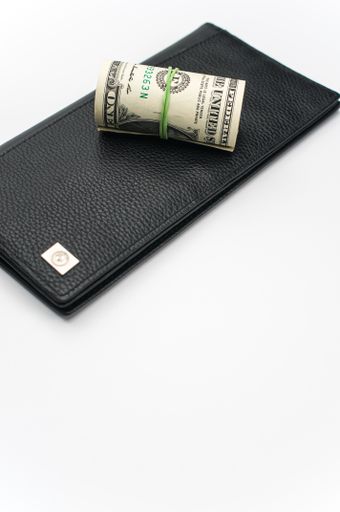 US dollars wad with luxury black leather wallet on a white background with copy space