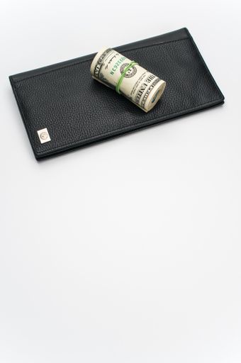 US dollars wad with luxury black leather wallet on a white background with copy space