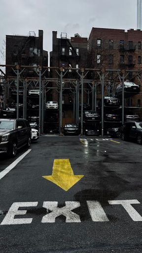 The New York City outdoor Parking lot with parked cars and yellow arrows on the ground.