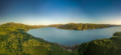 A mesmerizing view of a calm lake surrounded by mountains under a blue sky