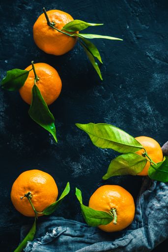 A vertical shot of mandarin orange fruits on a dark background