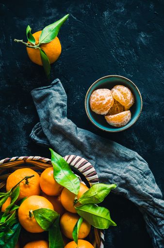 A vertical shot of mandarin orange fruits on a dark background