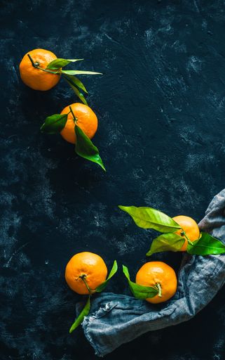 A vertical shot of mandarin orange fruits on a dark background